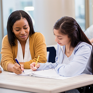 two women are working together and writing in a notebook